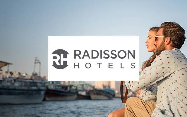 En man och en kvinna vid havet och Radisson hotels logotyp