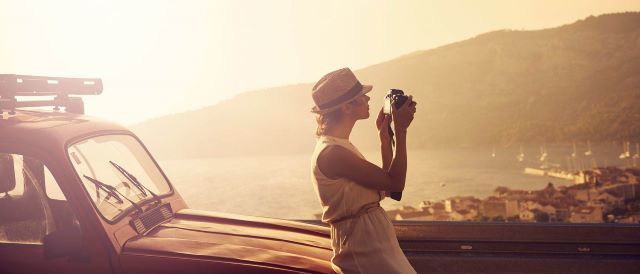 Fotograferande kvinna på bilsemester. Med re:member har du möjlighet att få reda på ditt saldo dygnet runt, världen över.